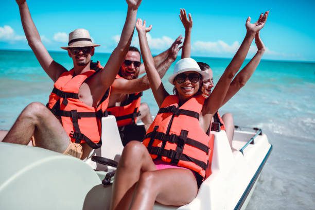 Friends Lifting Their Arms Up During Pedal Boat Fun On Sea