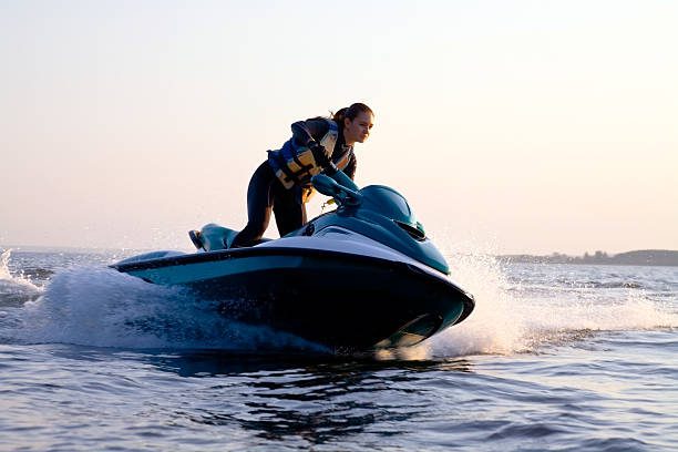 beautiful girl riding her jet skis in the sea at sunset. spray